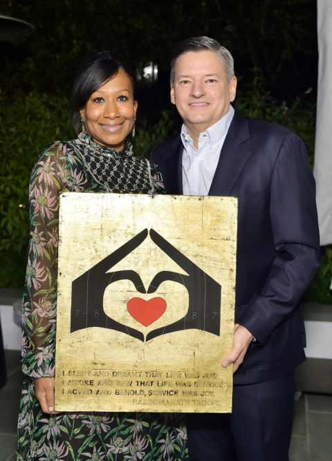 Two people hold up an A Sense of Home branded poster