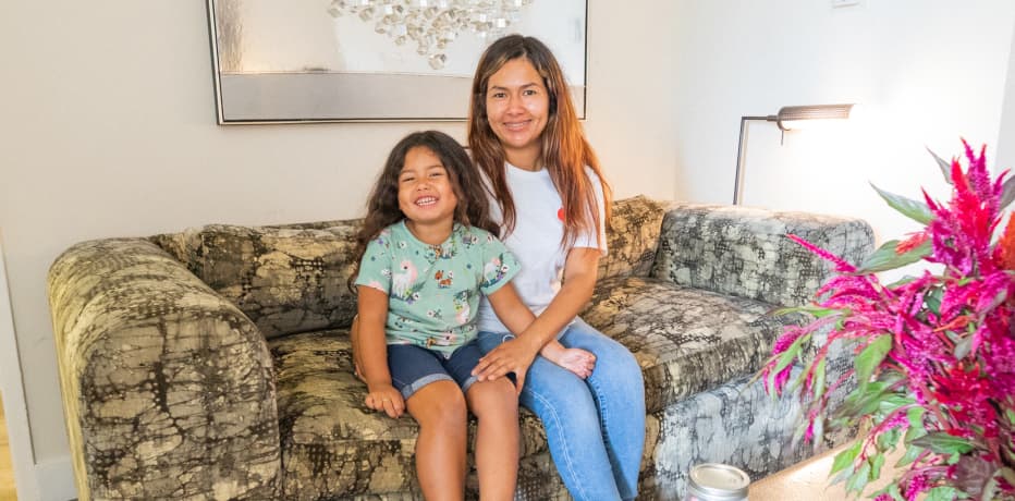 Mother and daughter sit smiling in their new furnished home