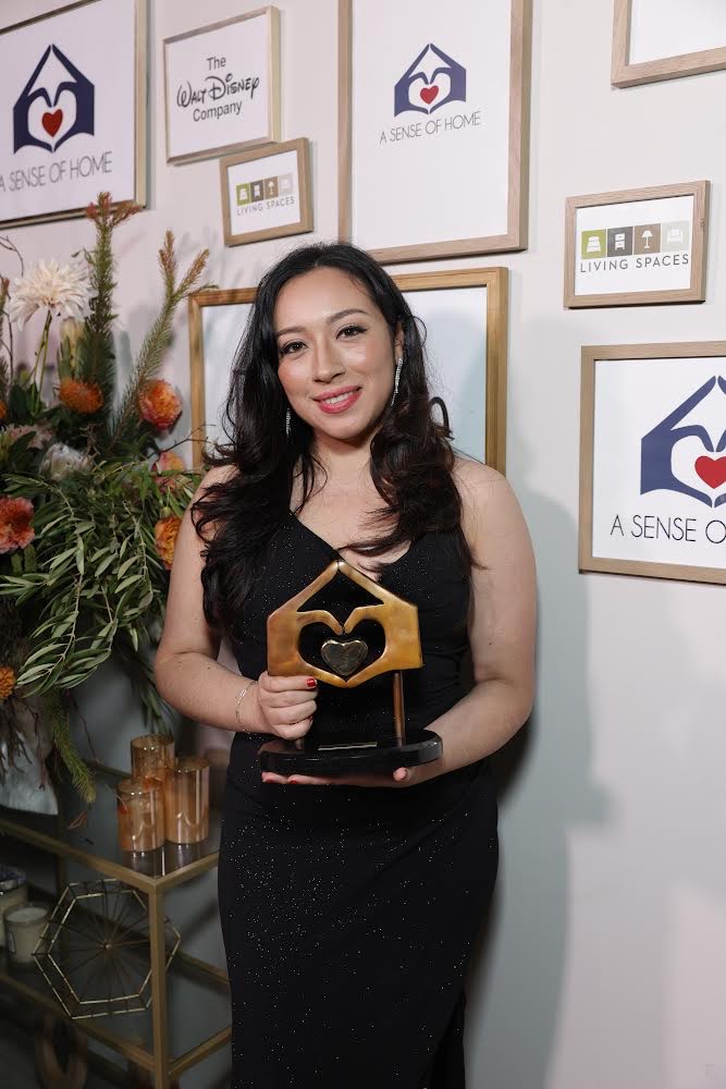 Becky Perez holding an award at the A Sense of Home Gala